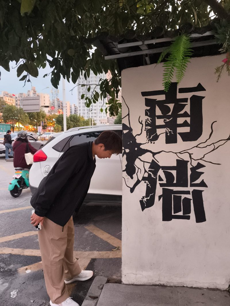 一个人在白墙前低头看着墙上的