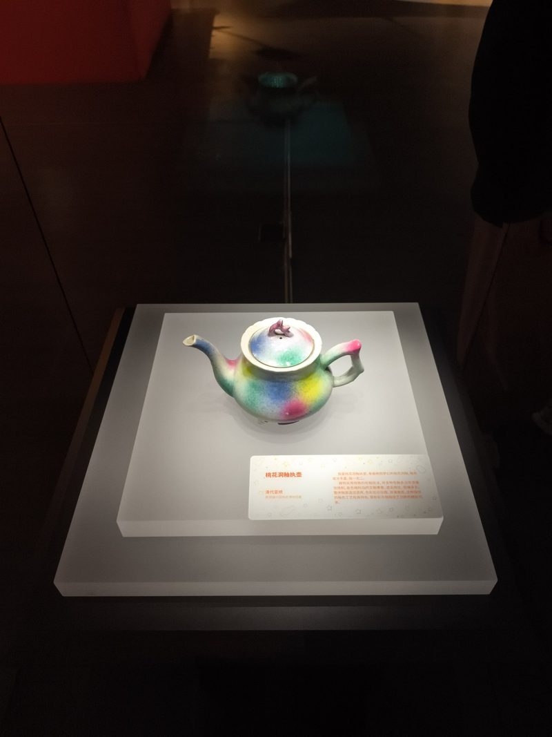 釉色青绿粉紫交融的小茶壶放在展台上