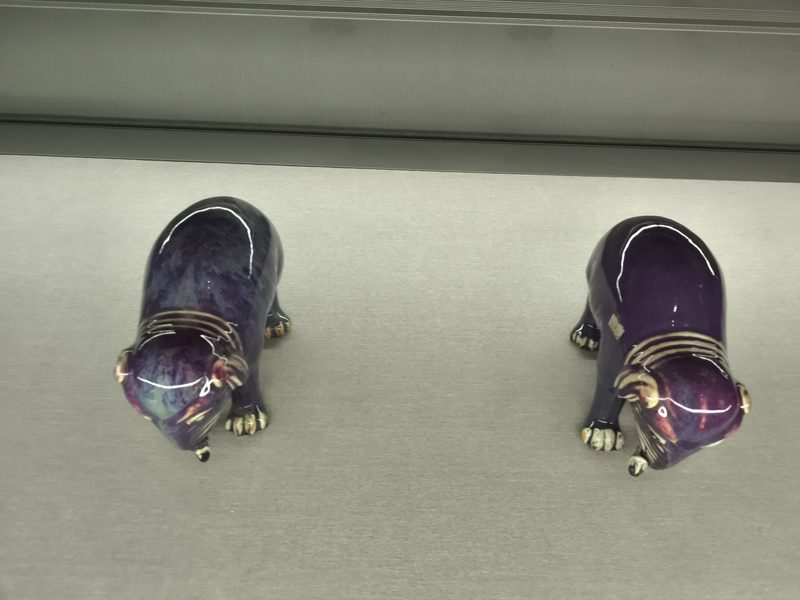 两只紫釉瓷兽低头伏在展台上